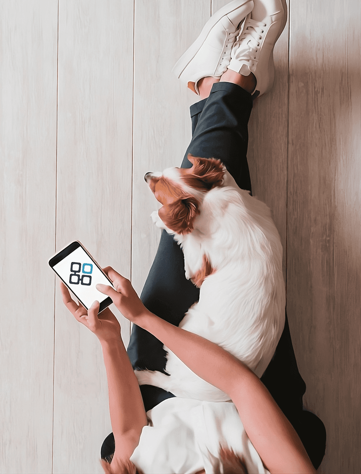 Photo of a person with a dog on their lap while on their mobile phone.